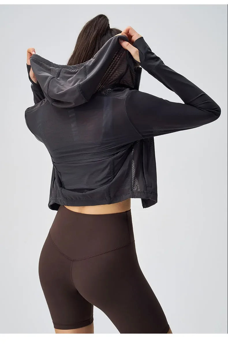 Back view of woman wearing breathable yoga clothes for women with black mesh hoodie and brown shorts