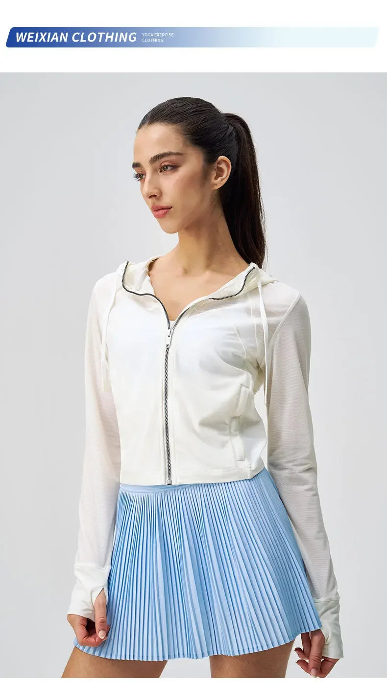 Woman wearing breathable yoga clothes for women including a white zip-up hoodie and blue pleated skirt