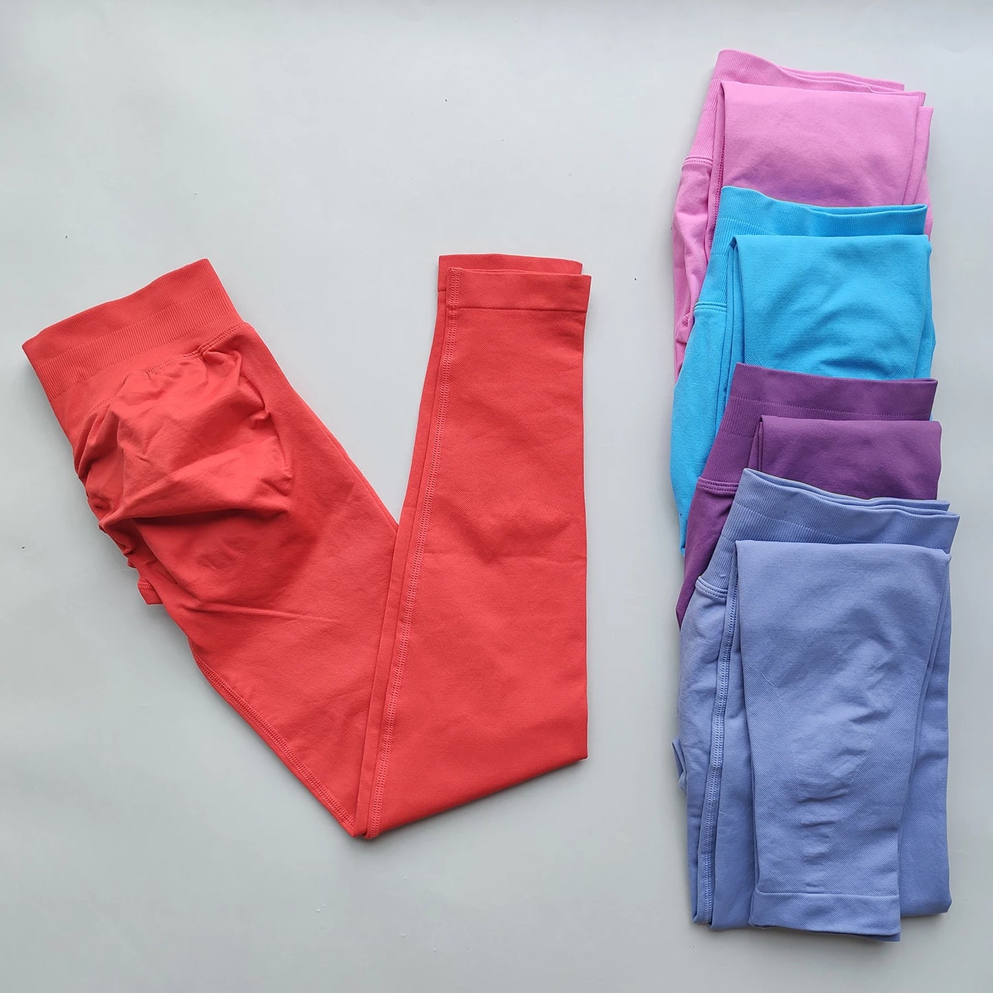 Woman Scrunch Bum Flare Leggings in coral and other colors folded on white background
