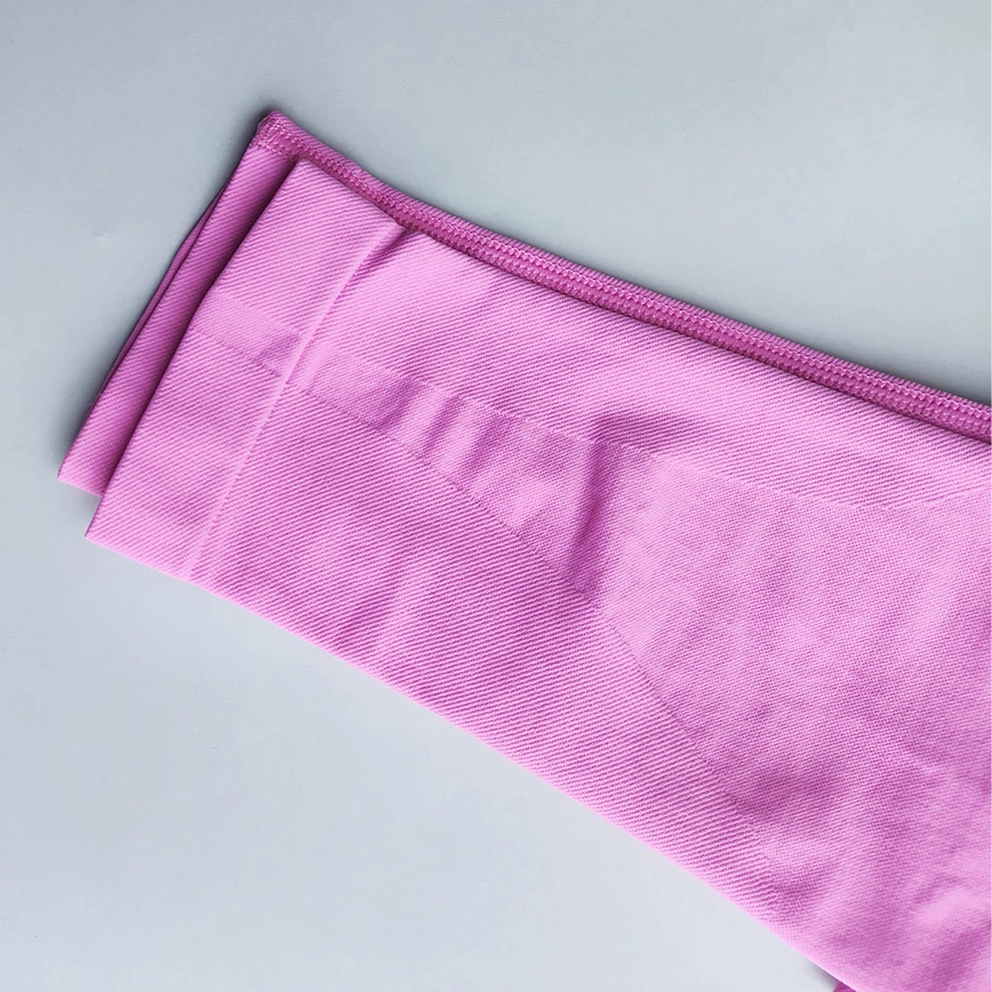 Pink Woman Scrunch Bum Flare Leggings folded on a light gray surface by KiKis