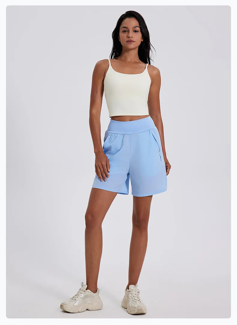 Woman wearing light blue women's high waist running shorts with pockets and white tank top