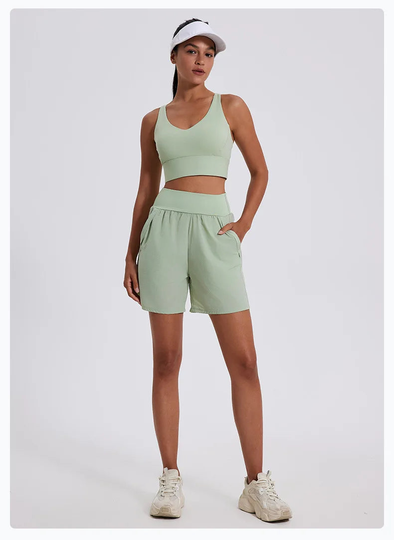 KiKis women's high waist running shorts in light green worn with matching sports bra and white visor