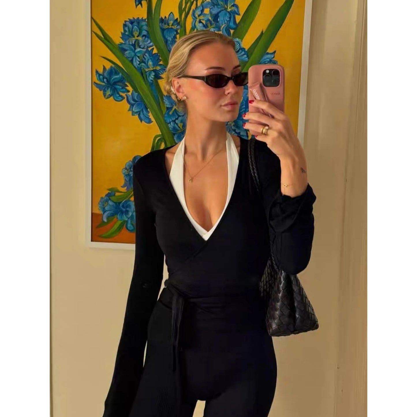 Woman wearing KiKis women's long sleeve yoga top in black taking a mirror selfie with sunglasses and a black bag