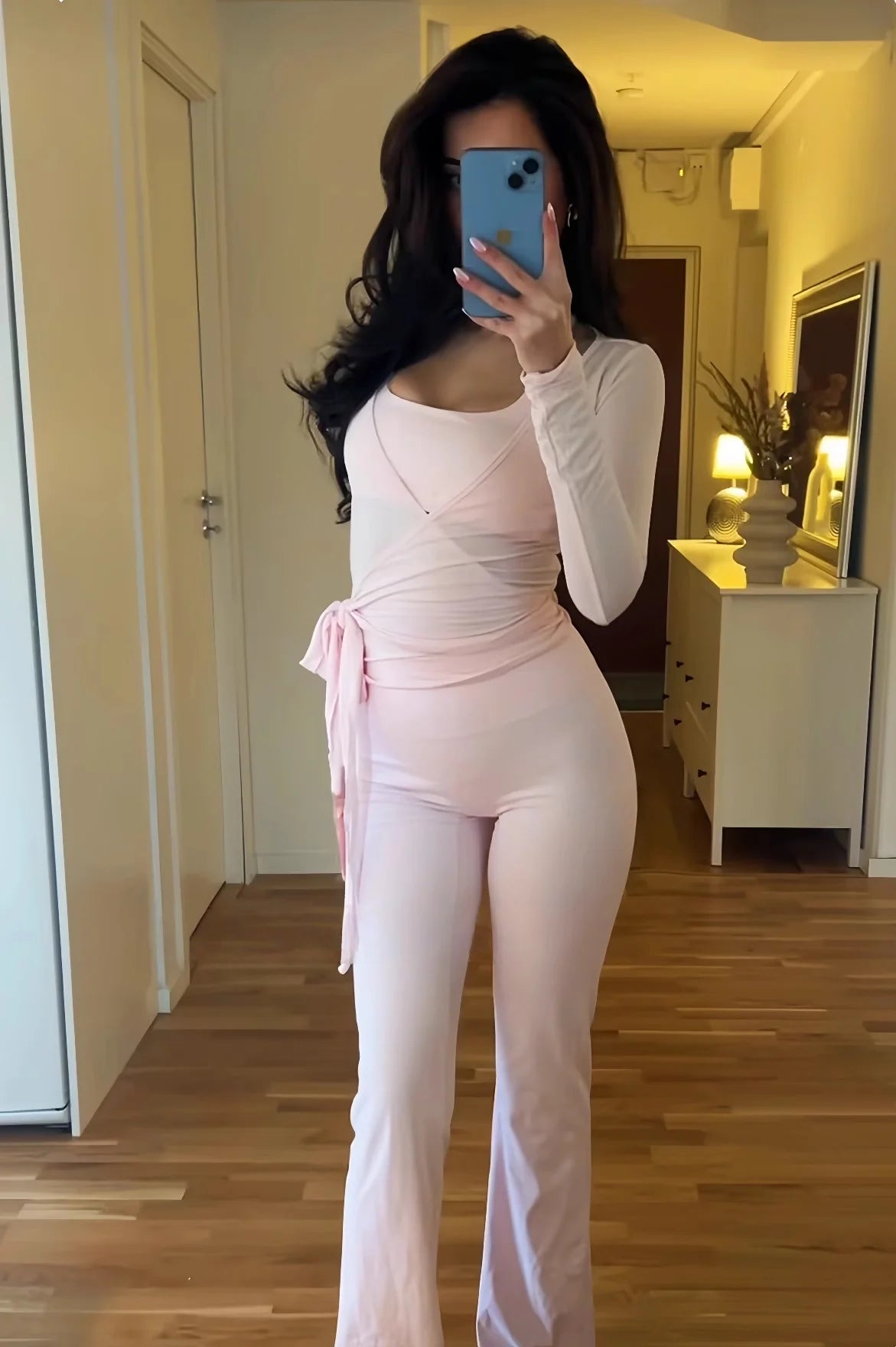 KiKis women's long sleeve yoga top in light pink styled with matching pants in a home setting
