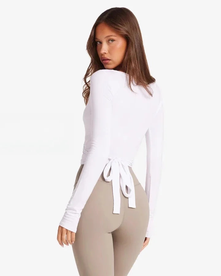 KiKis women's long sleeve yoga top in white with back tie detail and fitted design