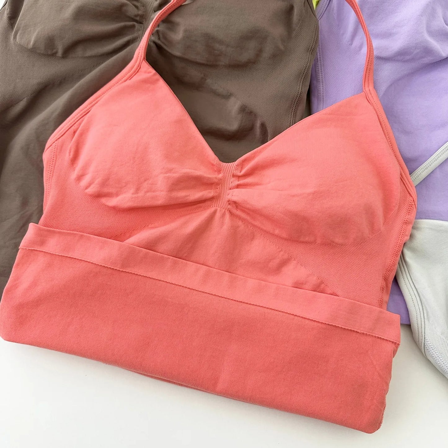 KiKis coral color Women's Backless Gym Top with adjustable straps laid on brown and purple fabric