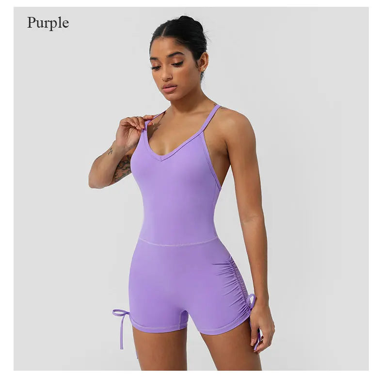 Purple women's cross back yoga jumpsuit by KiKis modeled on fit woman with adjustable side ties