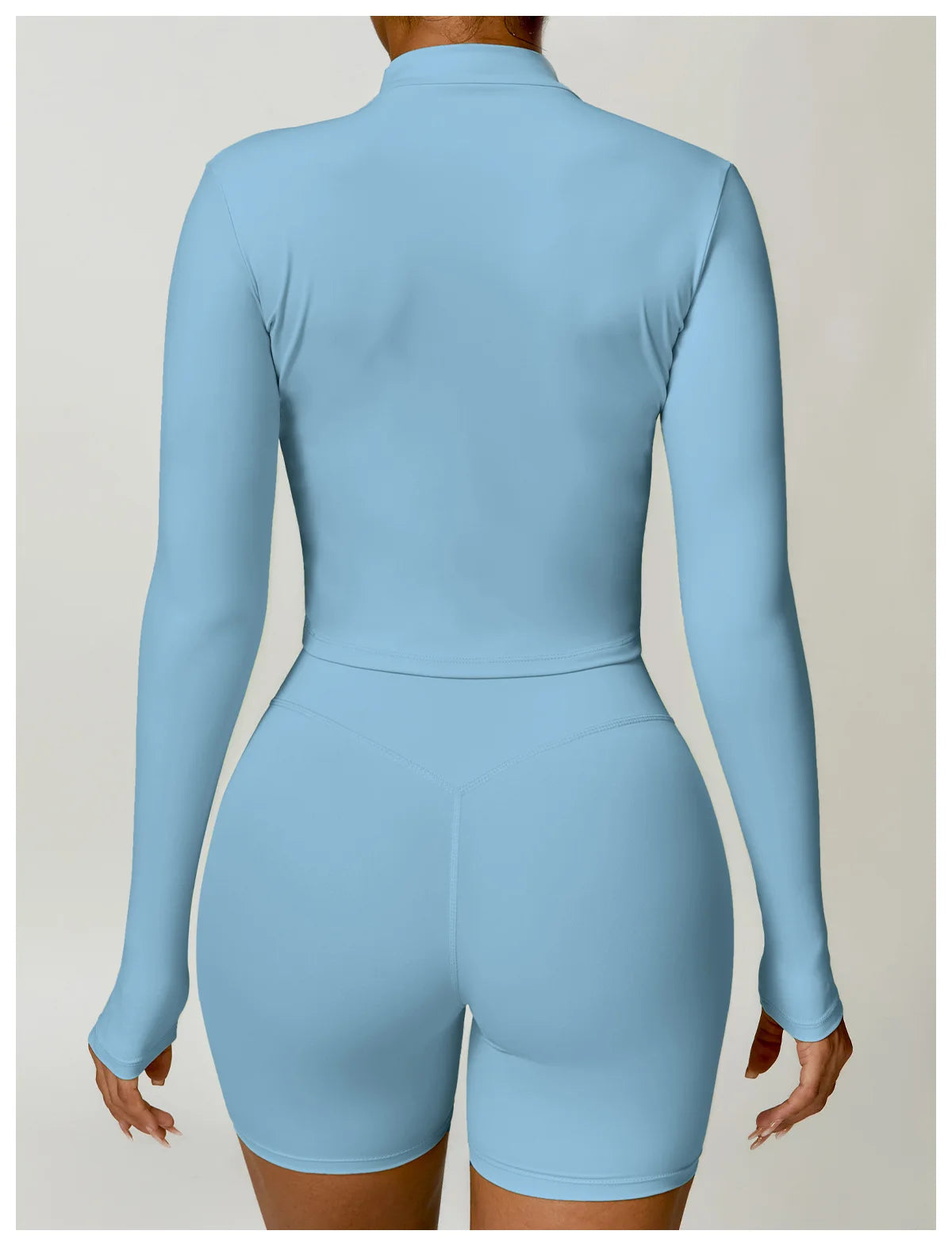 KiKis brand women's gym workout zip up top in light blue shown from back with long sleeves and fitted design