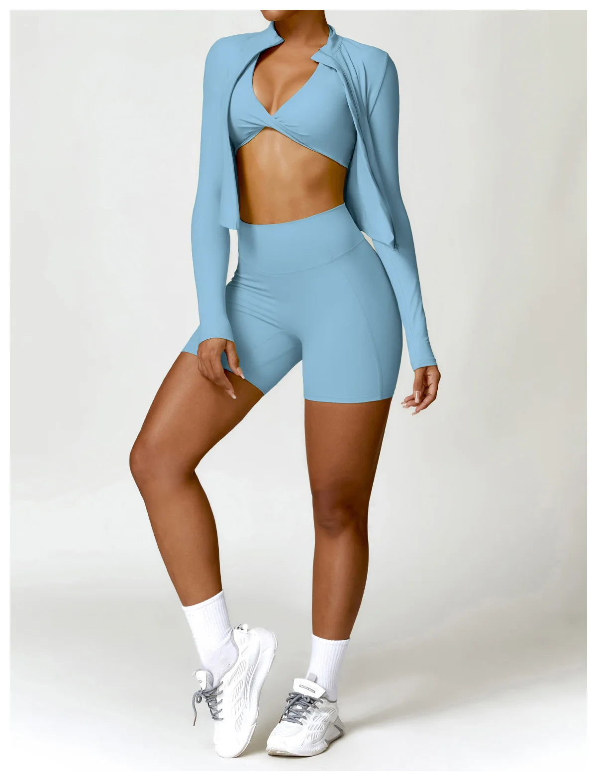 KiKis women's gym workout zip up top in light blue worn with matching high-waist shorts and white sneakers
