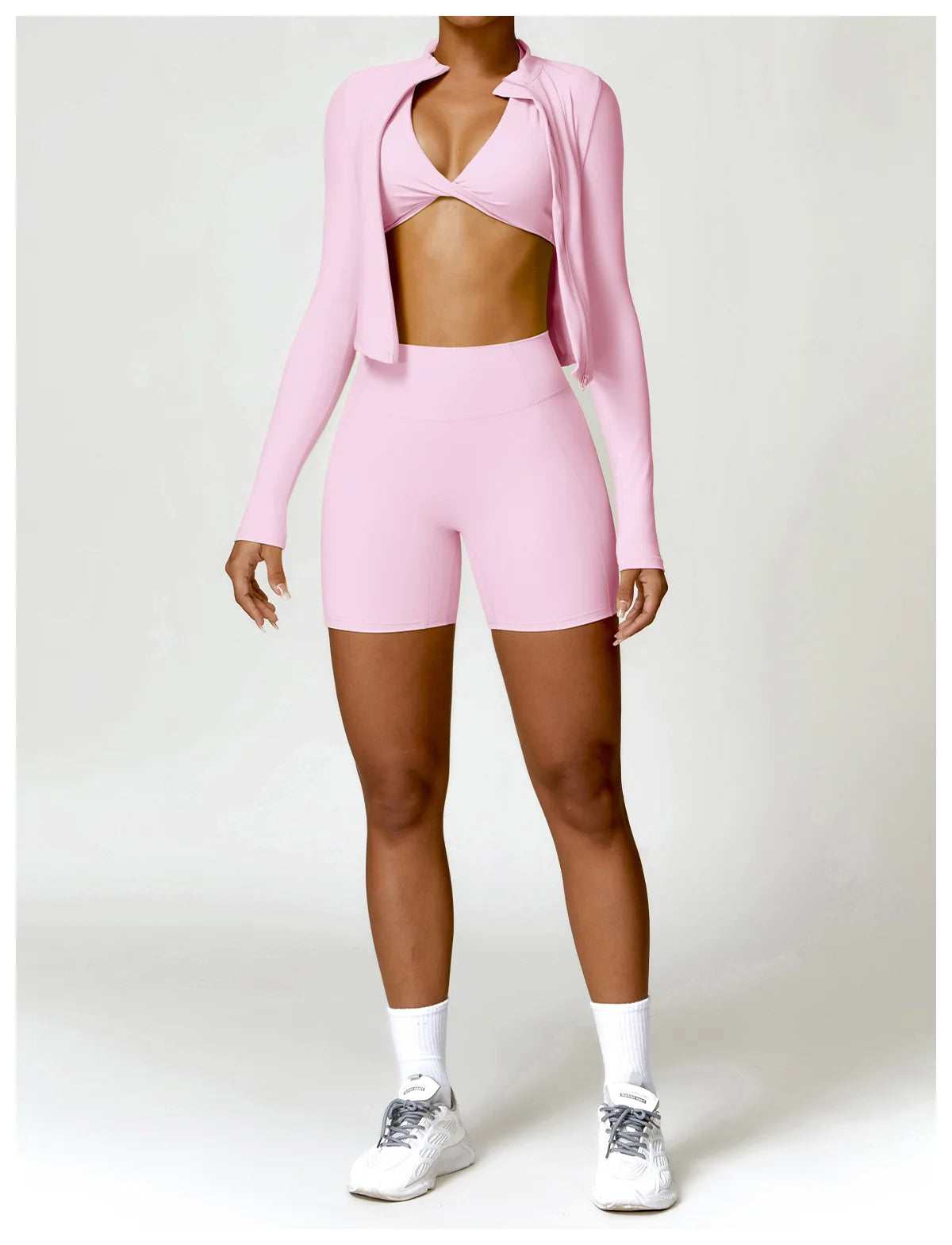 KiKis women's gym workout zip up top in pink worn with matching shorts and white sneakers