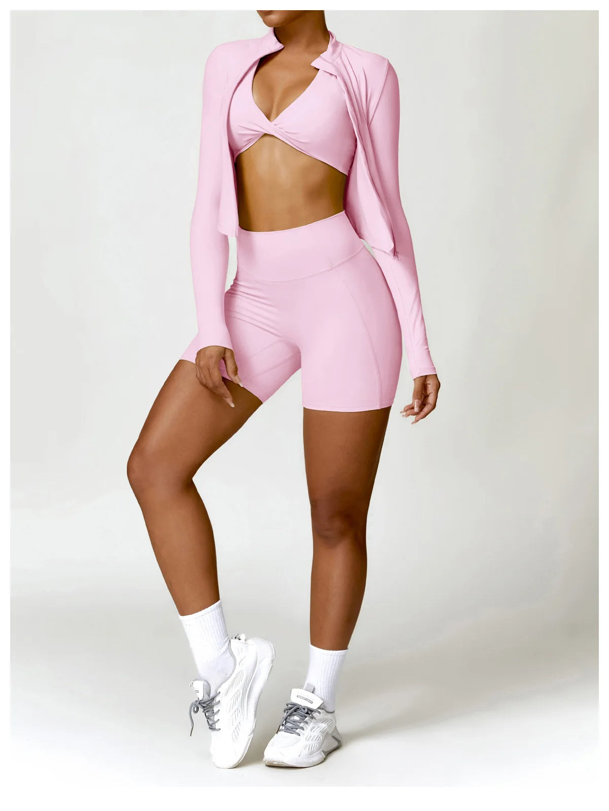 KiKis women's gym workout zip up top in pink paired with matching shorts and white sneakers