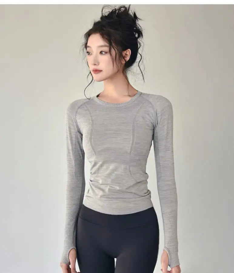 KiKis women's long sleeve yoga top in light gray worn with black leggings for fitness
