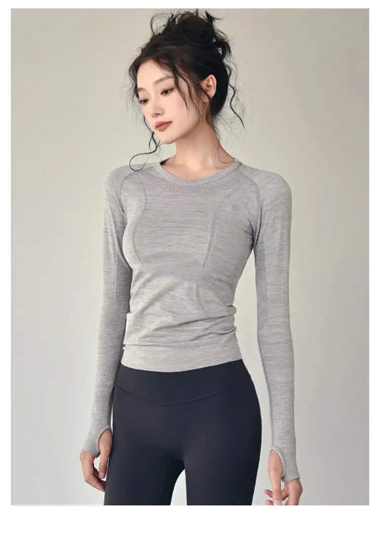 KiKis women's long sleeve yoga top in light gray with thumb holes, worn with black leggings