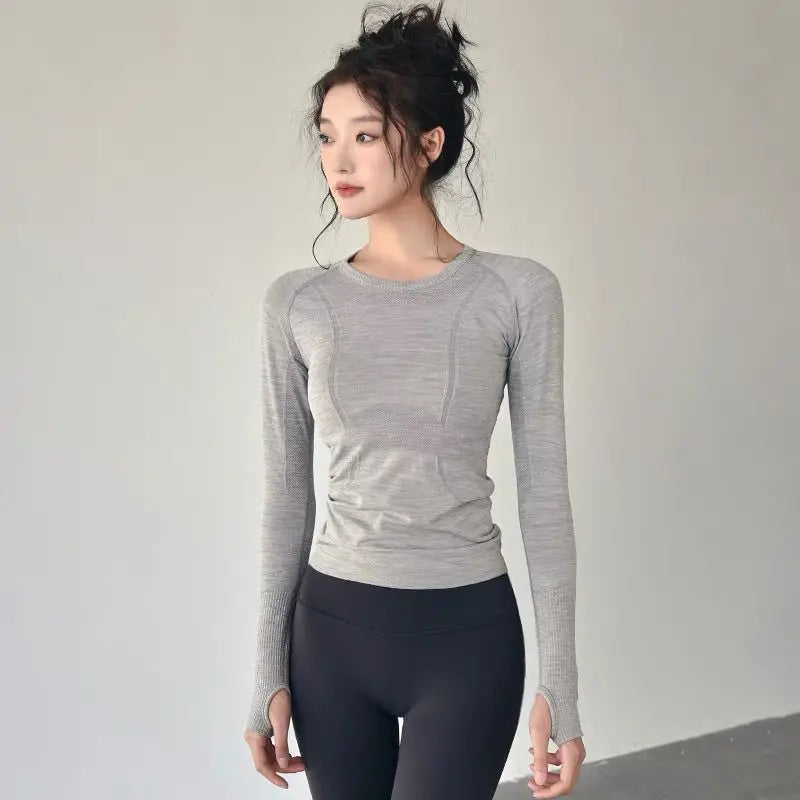 KiKis women's long sleeve yoga top in light gray worn with black leggings for workout flexibility