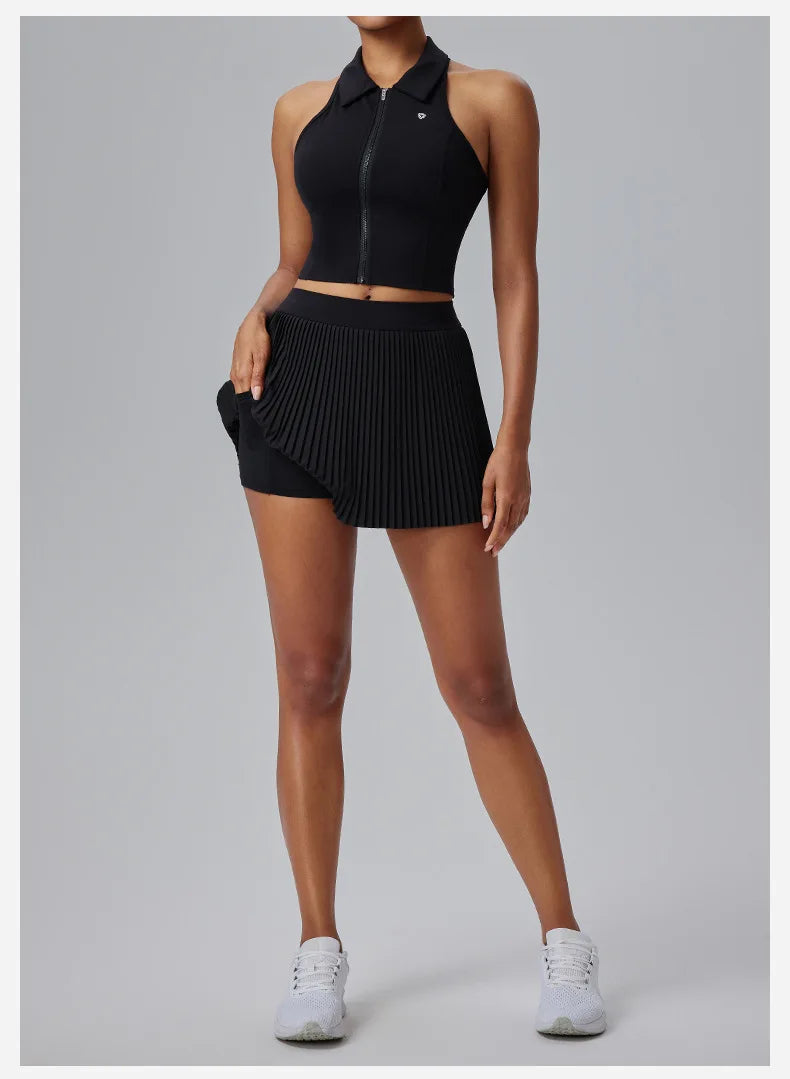 KiKis Women's Organ Pleated Tennis Skirt in black paired with a sleeveless zip-up top and white sneakers