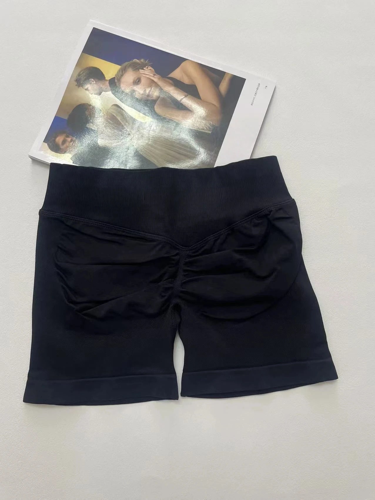 KiKis women's peach hip yoga shorts in black laid flat on white background