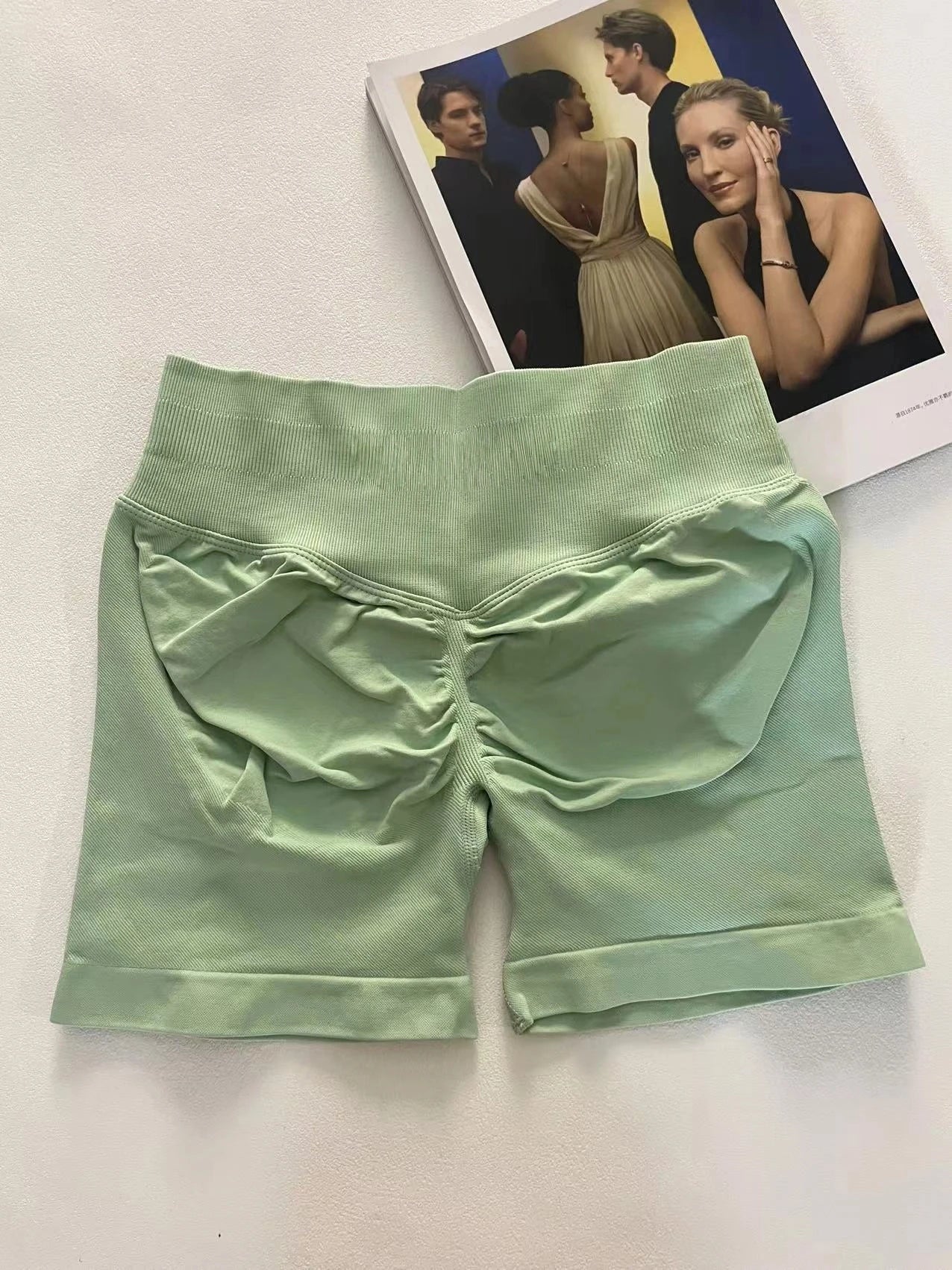 KiKis women's peach hip yoga shorts in light green laid flat showing ruched back detail