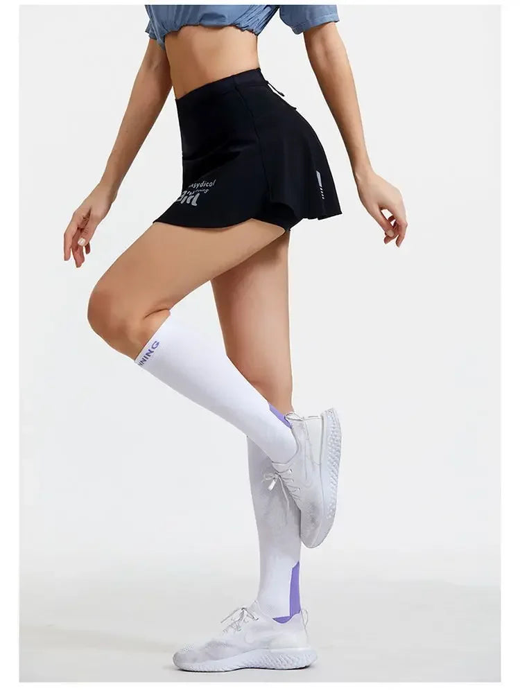 KiKis women's quick dry tennis skirt in black worn with white sports socks and sneakers