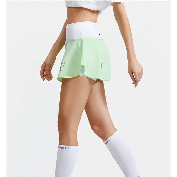 KiKis women's quick dry tennis skirt in light green with a white waistband worn with white knee-high socks