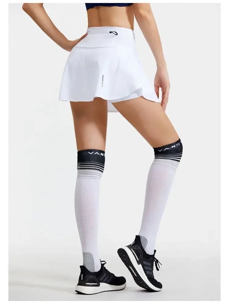 KiKis women's quick dry tennis skirt in white worn with black sneakers and knee-high white socks