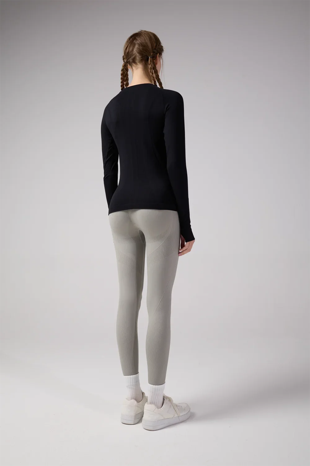 Back view of a woman wearing KiKis women's quick dry workout shirt in black with gray leggings