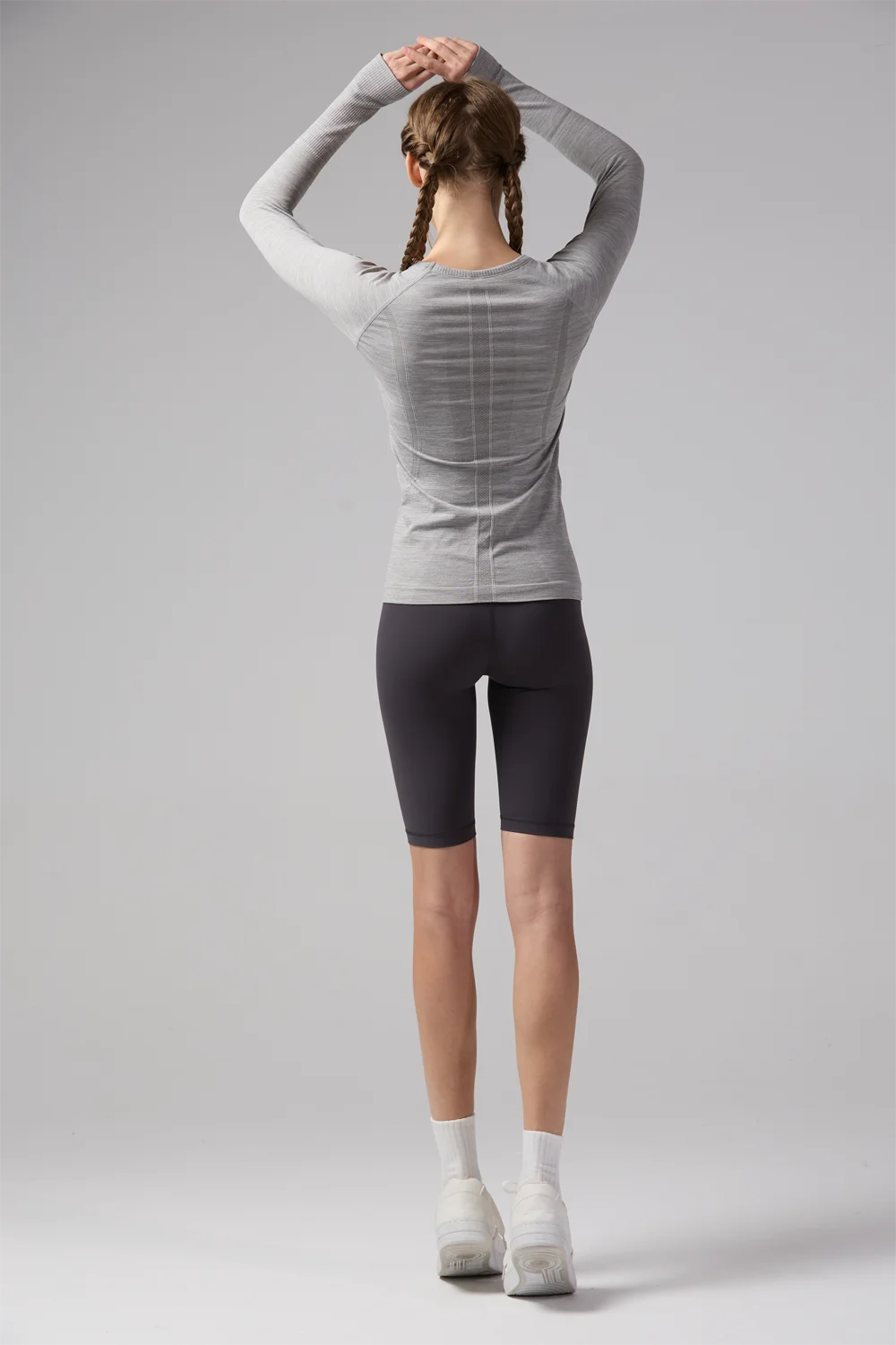 Woman wearing KiKis women's quick dry workout shirt in gray with long sleeves and finger holes