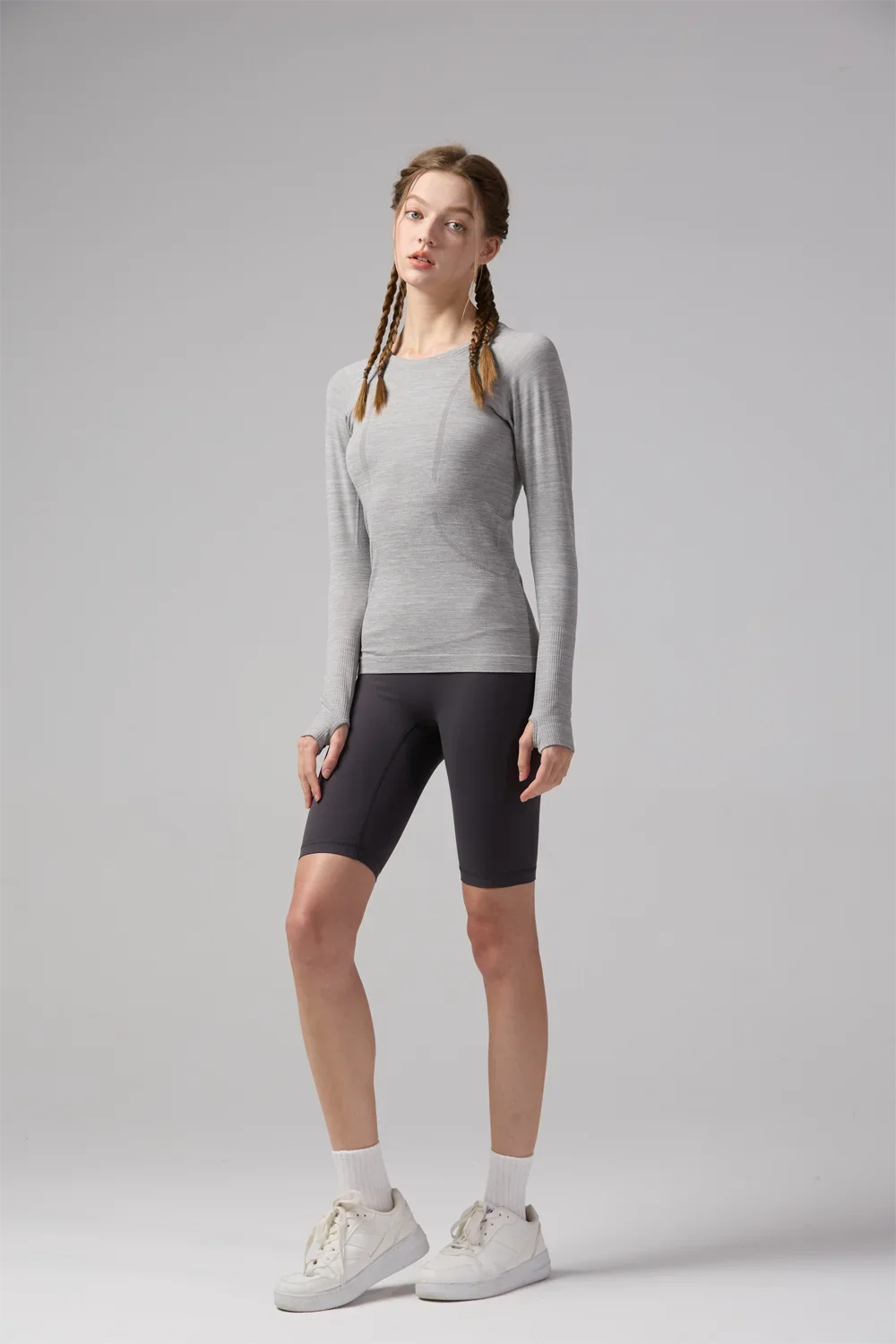 KiKis women's quick dry workout shirt in light gray worn with black biker shorts and white sneakers