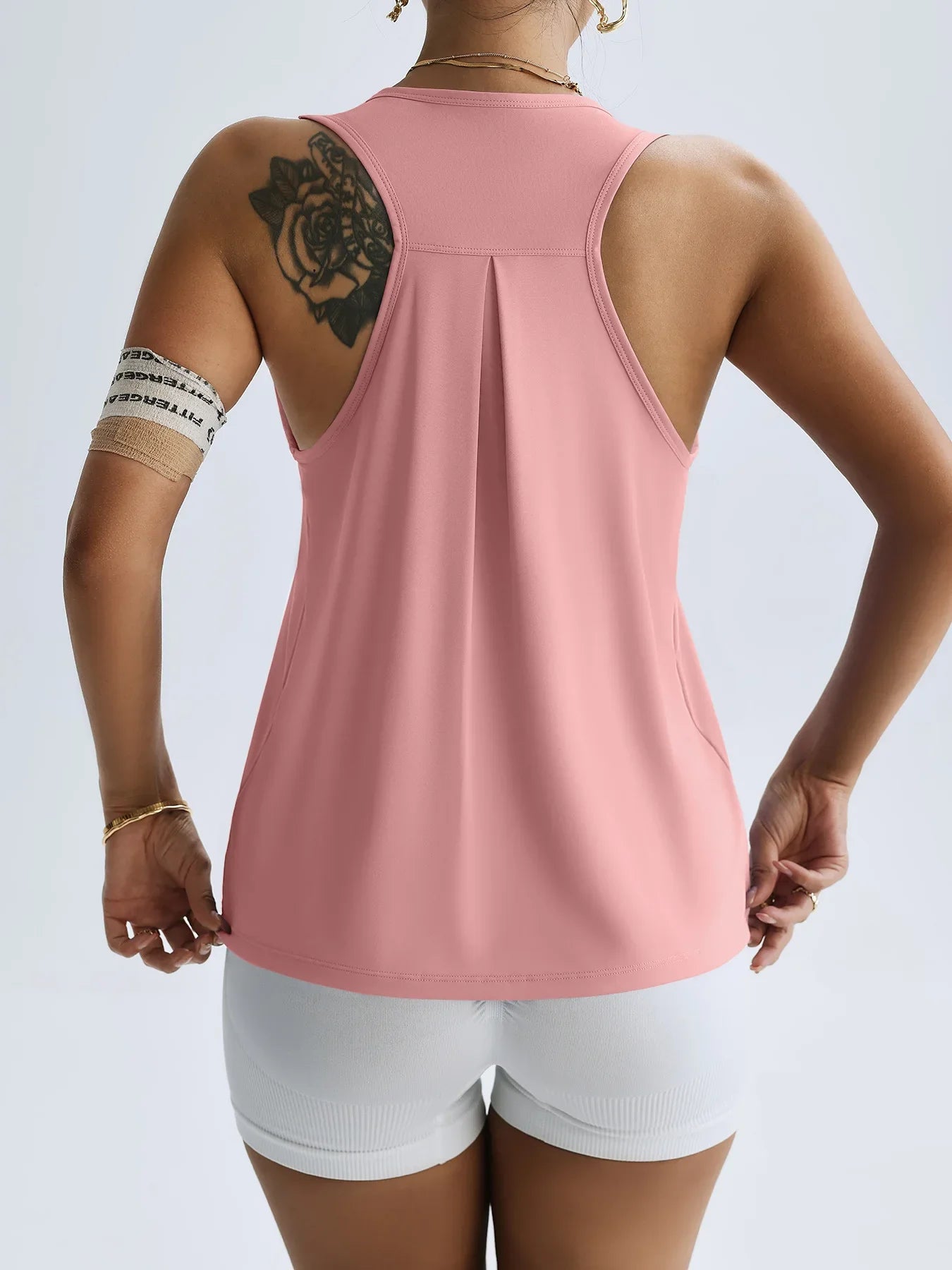 Back view of a woman wearing a pink women's quick dry yoga top by KiKis with racerback design