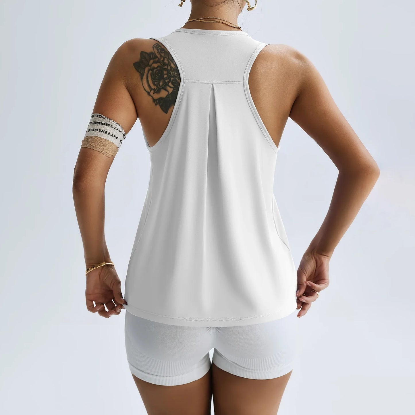 Back view of a woman wearing a white women's quick dry yoga top and matching shorts