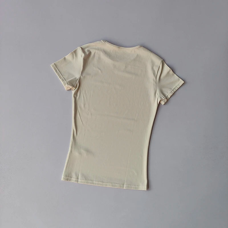 KiKis beige women's quick-dry yoga tops with short sleeves laid flat on gray background