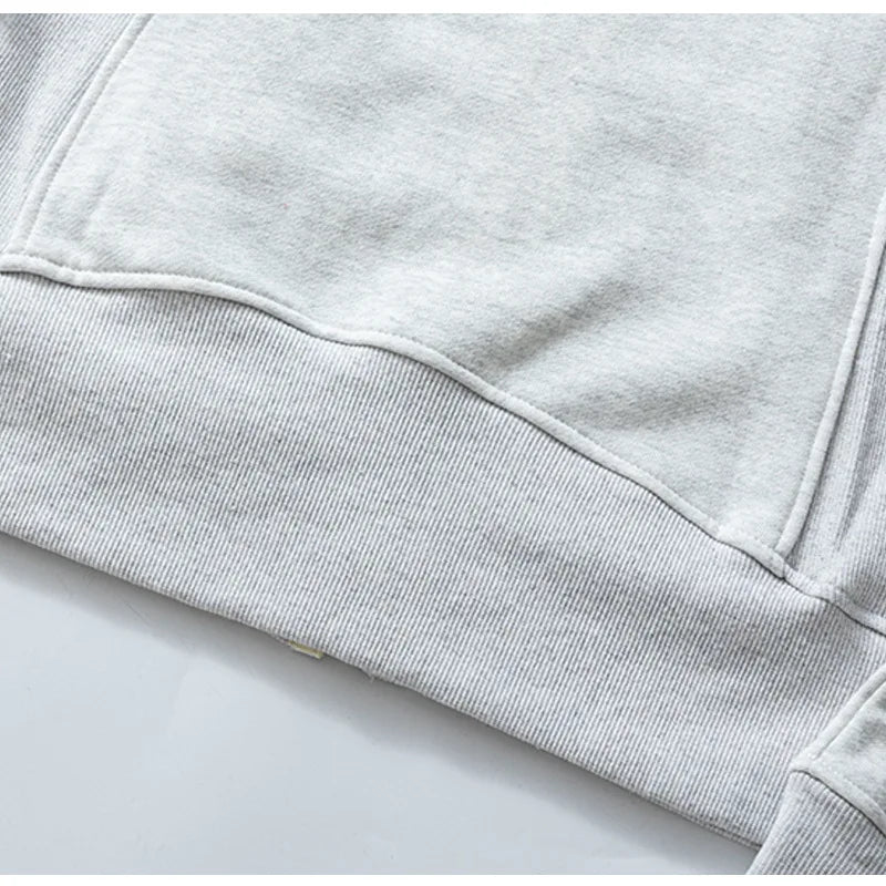 Close-up of light gray fabric and ribbed hem on women's running zip up hoodie by KiKis