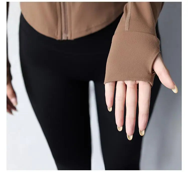 Close-up of a woman's hand wearing a brown women's slim fit yoga jacket with thumb hole sleeves