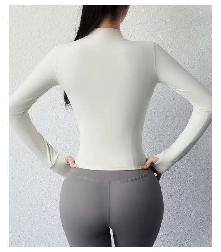 Back view of a woman wearing a women's slim fit yoga jacket in light color paired with gray leggings