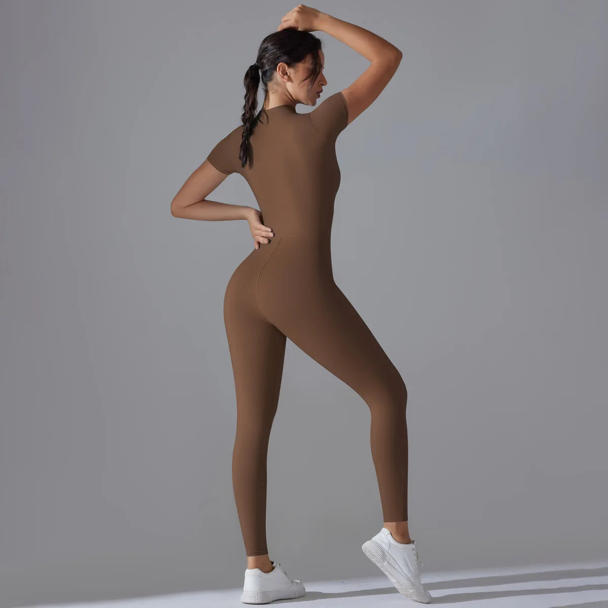 KiKis brown women's zipper yoga jumpsuit with short sleeves and fitted design worn with white sneakers