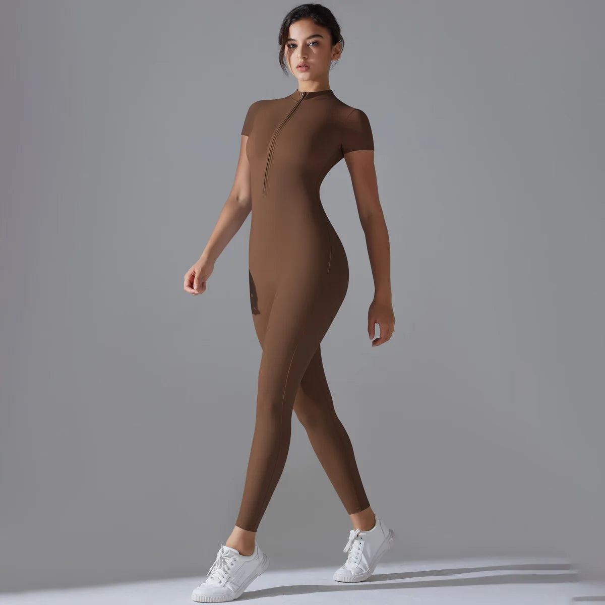 KiKis women's zipper yoga jumpsuit in brown with short sleeves modeled with white sneakers