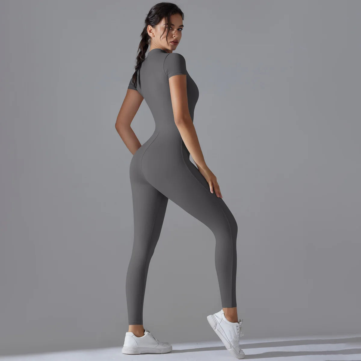 KiKis women's zipper yoga jumpsuit in gray with short sleeves and fitted design paired with white sneakers