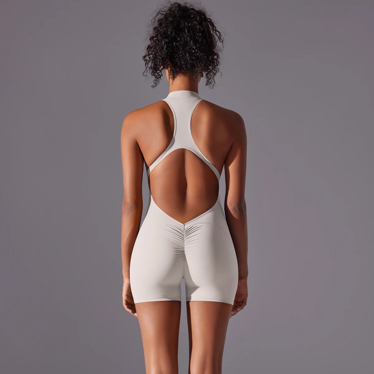 KiKis backless gym bodysuit for women in light beige with racerback design and fitted shorts