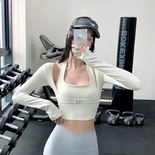 Woman wearing sexy women's yoga crop top in white with long sleeves posing in gym with kettlebells