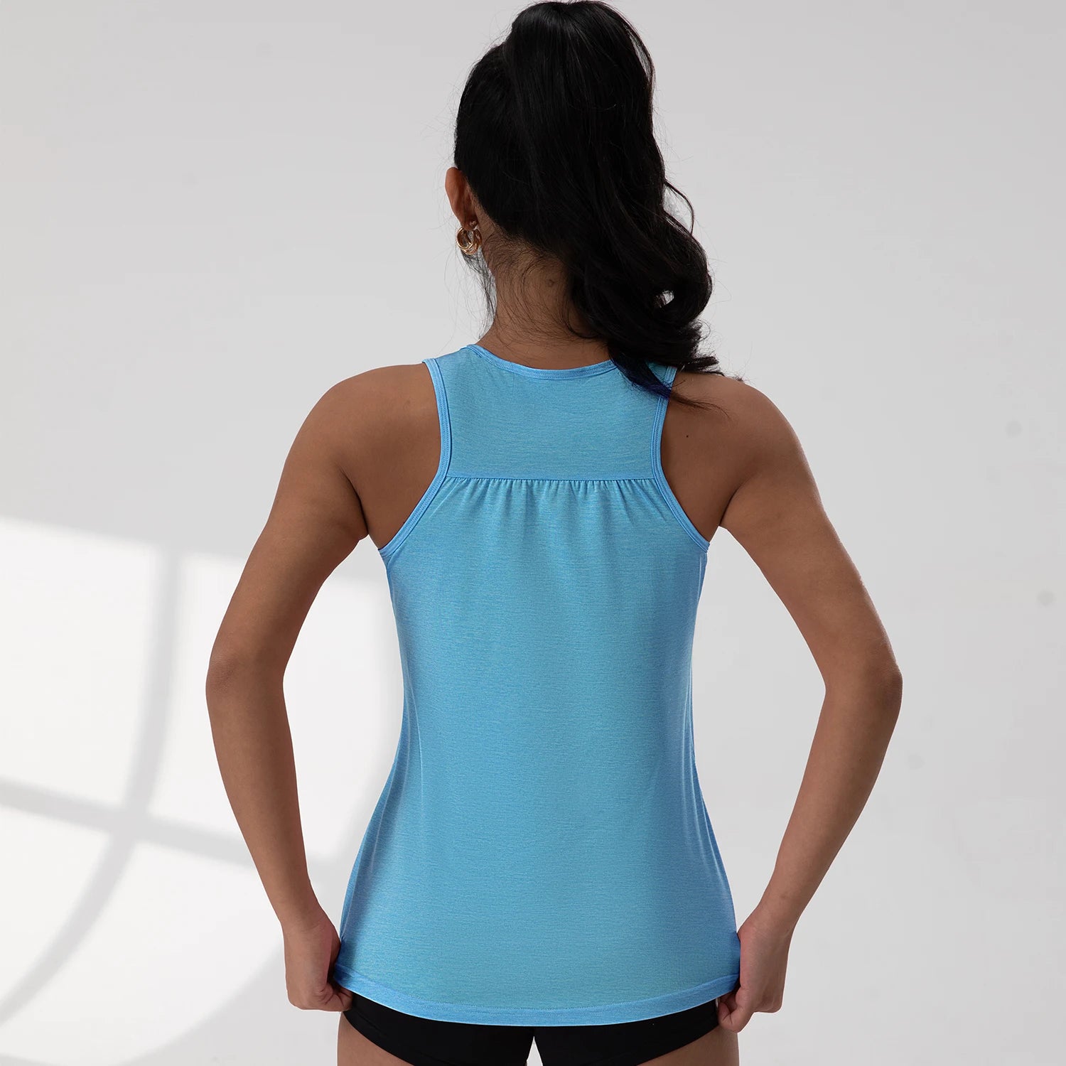 KiKis blue round neck sleeveless gym top worn by woman shown from the back