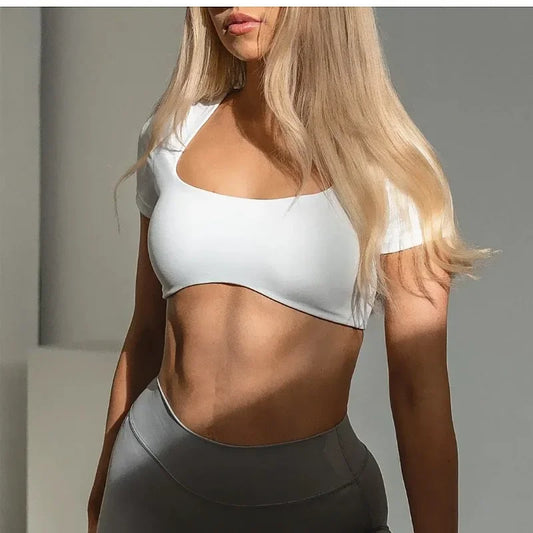 KiKis women's short sleeve sports crop top in white worn with gray workout leggings