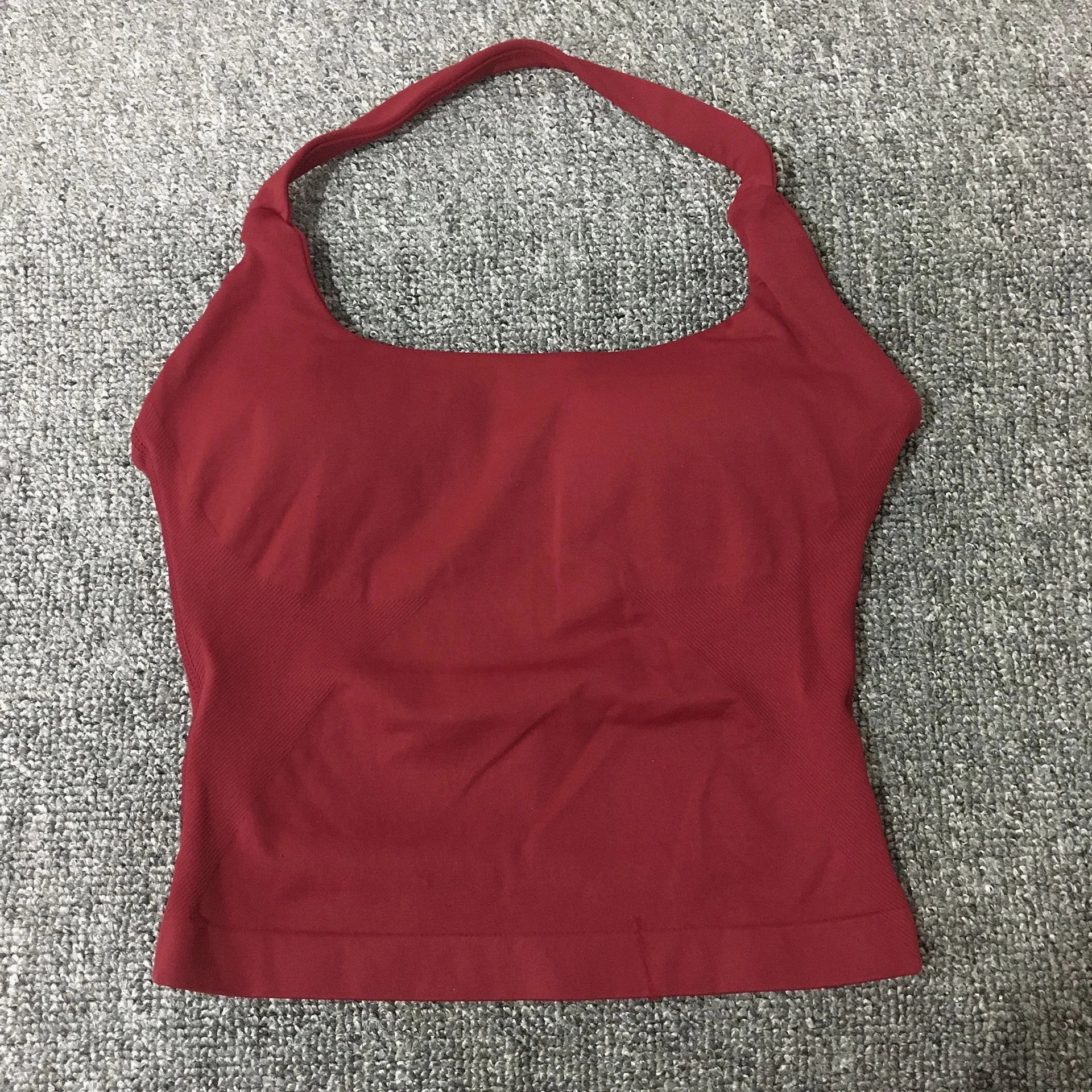 KiKis seamless backless sports tank top in deep red laid flat on gray carpet