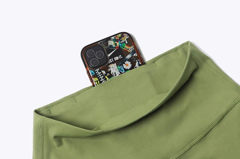 KiKis womens bell bottom yoga pants in green with hidden pocket holding a smartphone