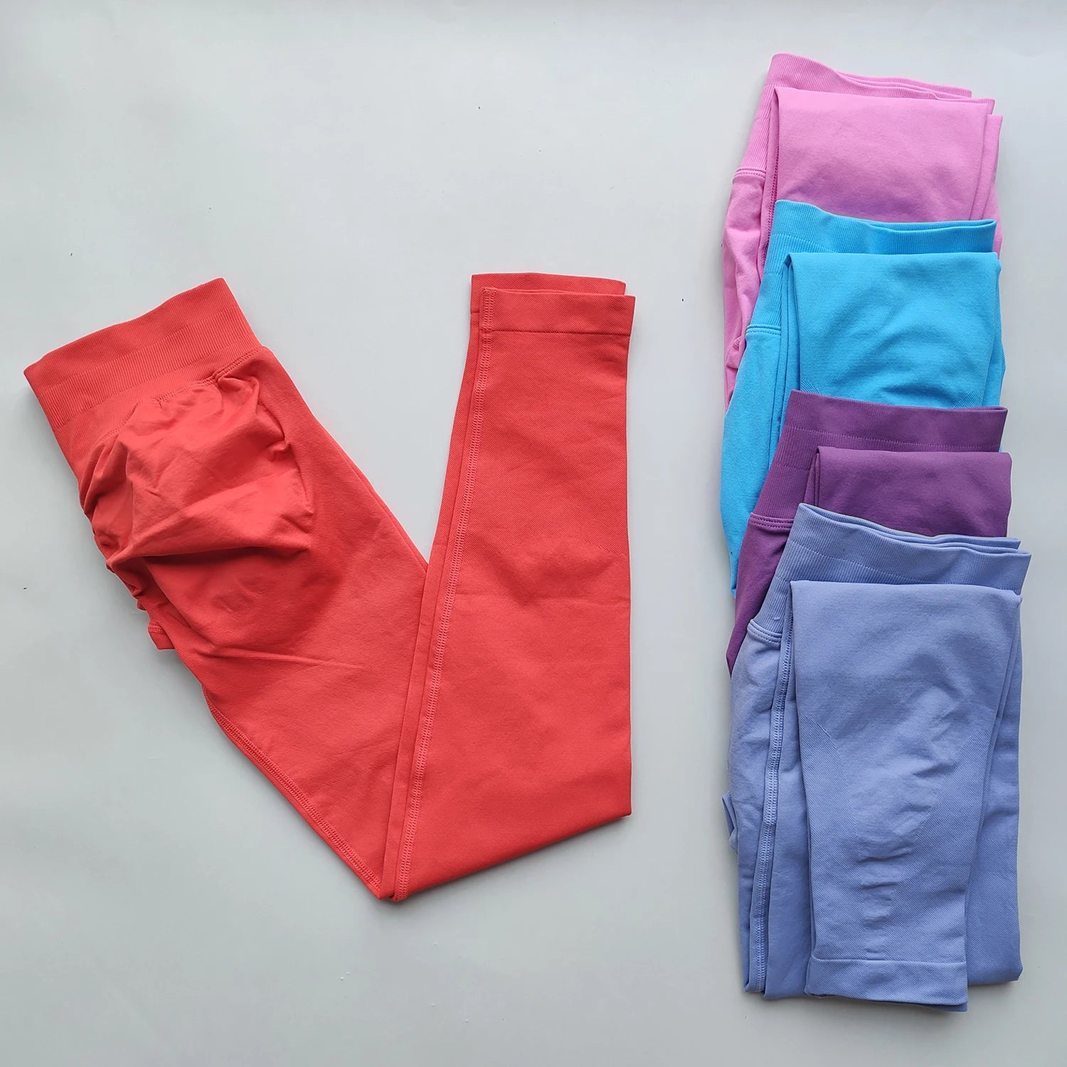 Woman Scrunch Bum Flare Leggings in coral and other colors folded on white background