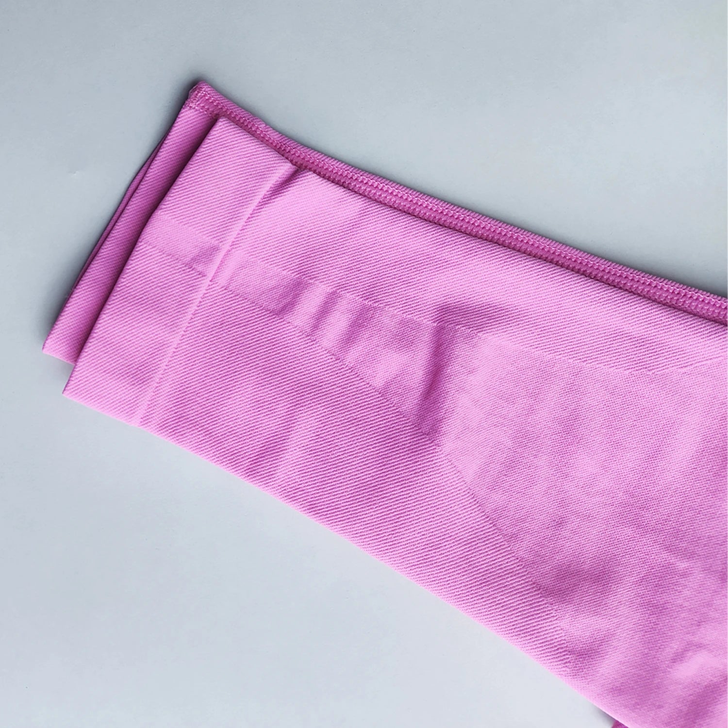 Pink Woman Scrunch Bum Flare Leggings folded on a light gray surface by KiKis
