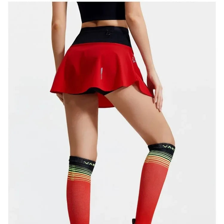 KiKis women's quick dry tennis skirt in red with black waistband worn with colorful knee-high socks