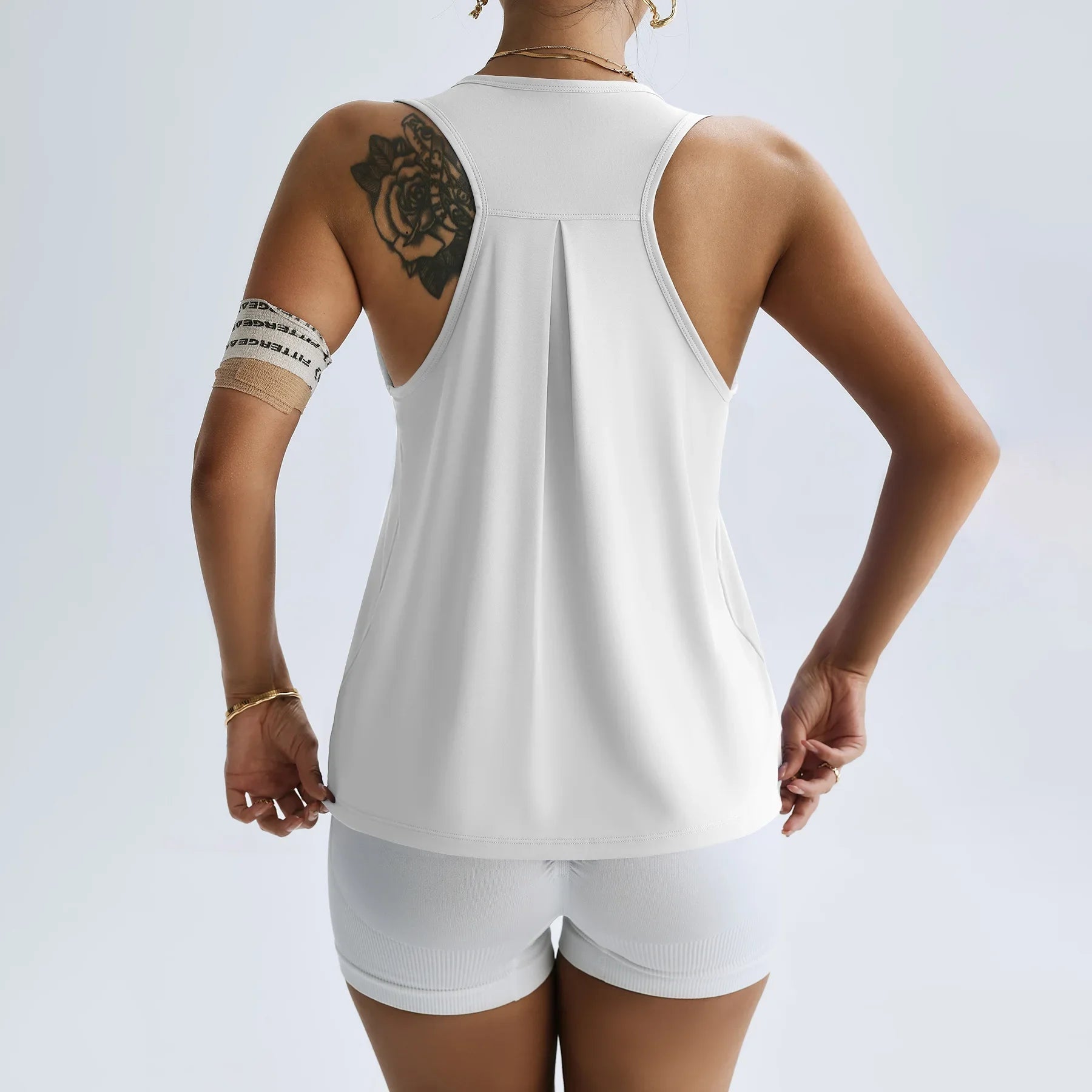 Back view of a woman wearing a white women's quick dry yoga top and matching shorts